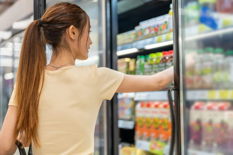 Woman grabbing product from dairy shelf.